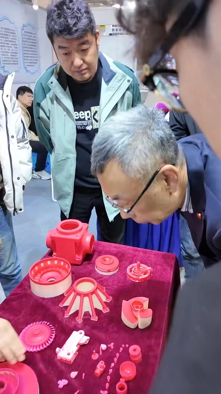 Visiteur examinant des modèles industriels de cire imprimés en 3D sur l'exposition Cprint 3D