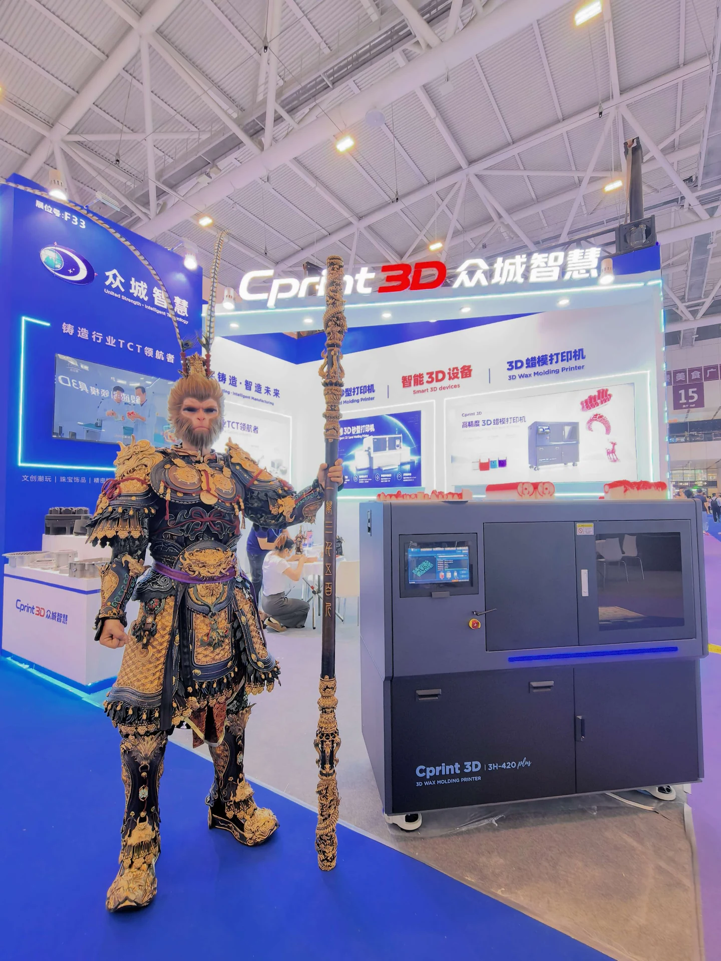 O intérprete de Black Myth: Wukong ao lado da impressora de cera 3H-420 Plus MJP da Cprint3D, com componentes fundidos do figurino e o bastão Jingubang