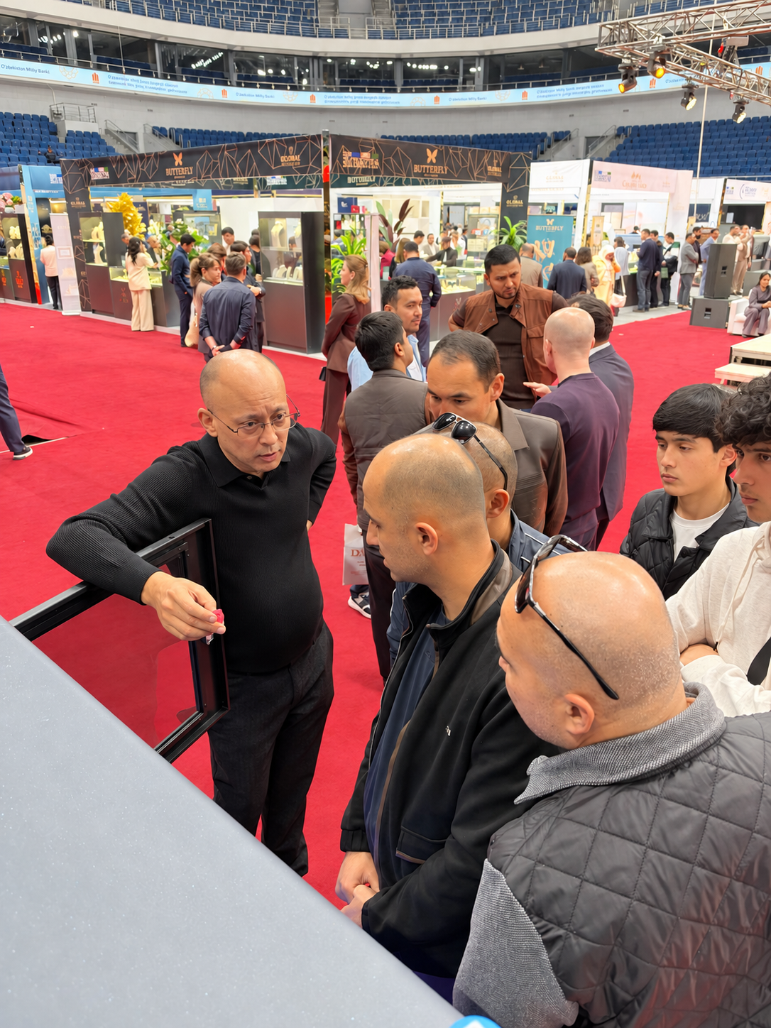 A presenter holding a red wax model while explaining it to visitors beside the printer