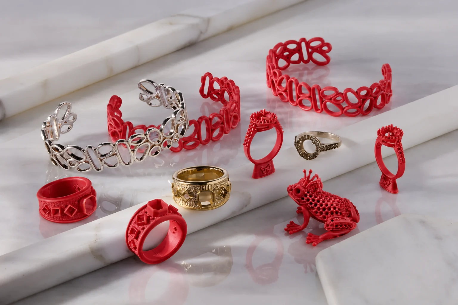 Red ring, openwork bracelet and frog-shaped patterns displayed beside metal-finish jewelry on a marble surface