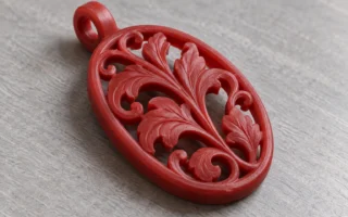 Modèle de pendentif en cire rouge à relief végétal et ajours sur un établi