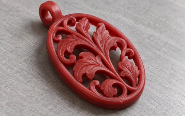 Modèle de pendentif en cire rouge à relief végétal et ajours sur un établi
