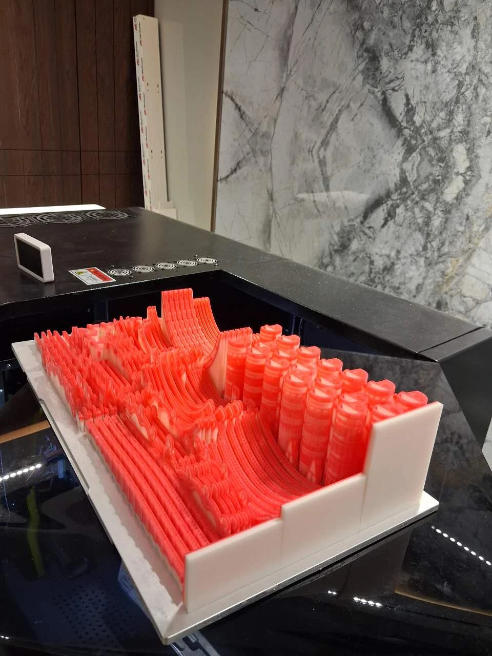 Modelos de cera vermelha de diferentes alturas com suporte branco na plataforma de impressão
